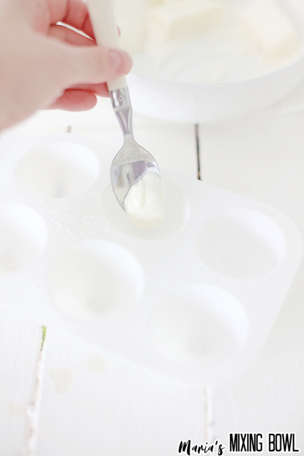 Spoon dropping white chocolate into silicon mold