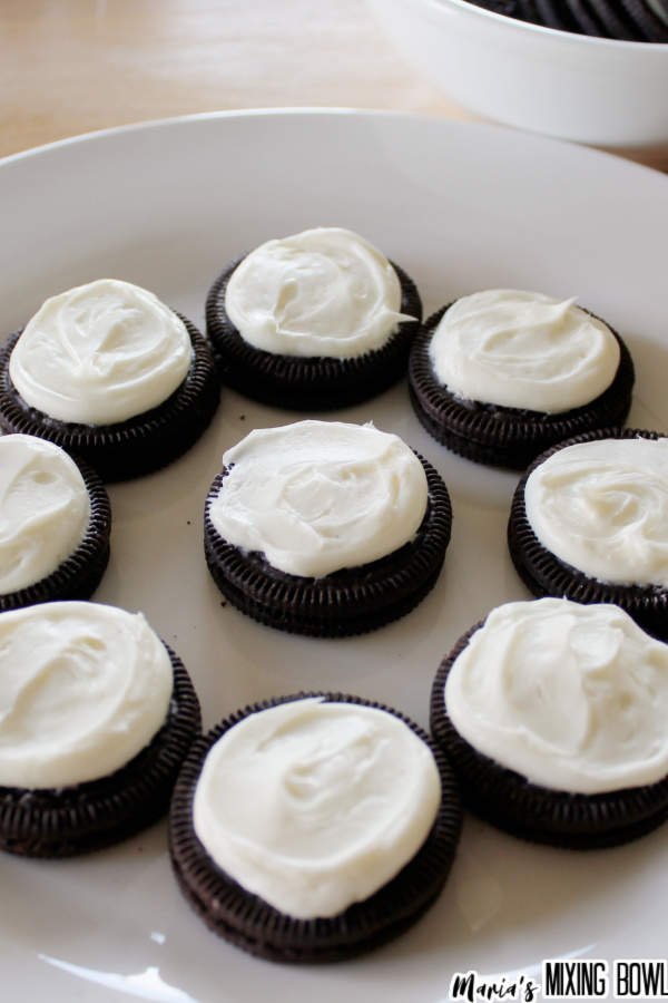 Oreos topped with frosting on white plate