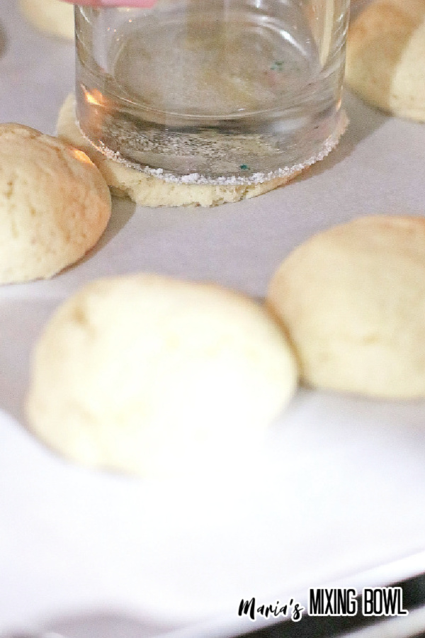 Closeup shot of sugar cookies being flattened with bottom of glass