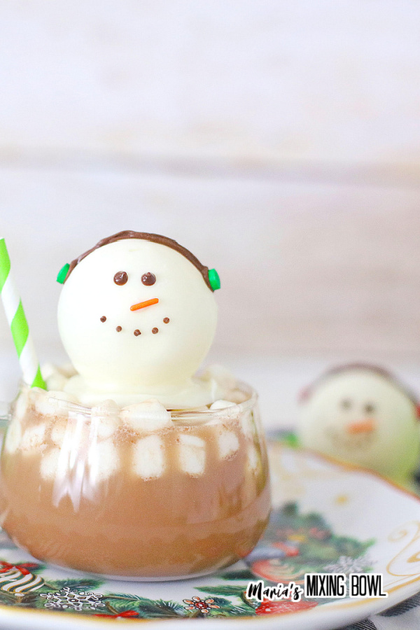 Snowman hot cocoa bomb on plate with another hot cocoa bomb in background