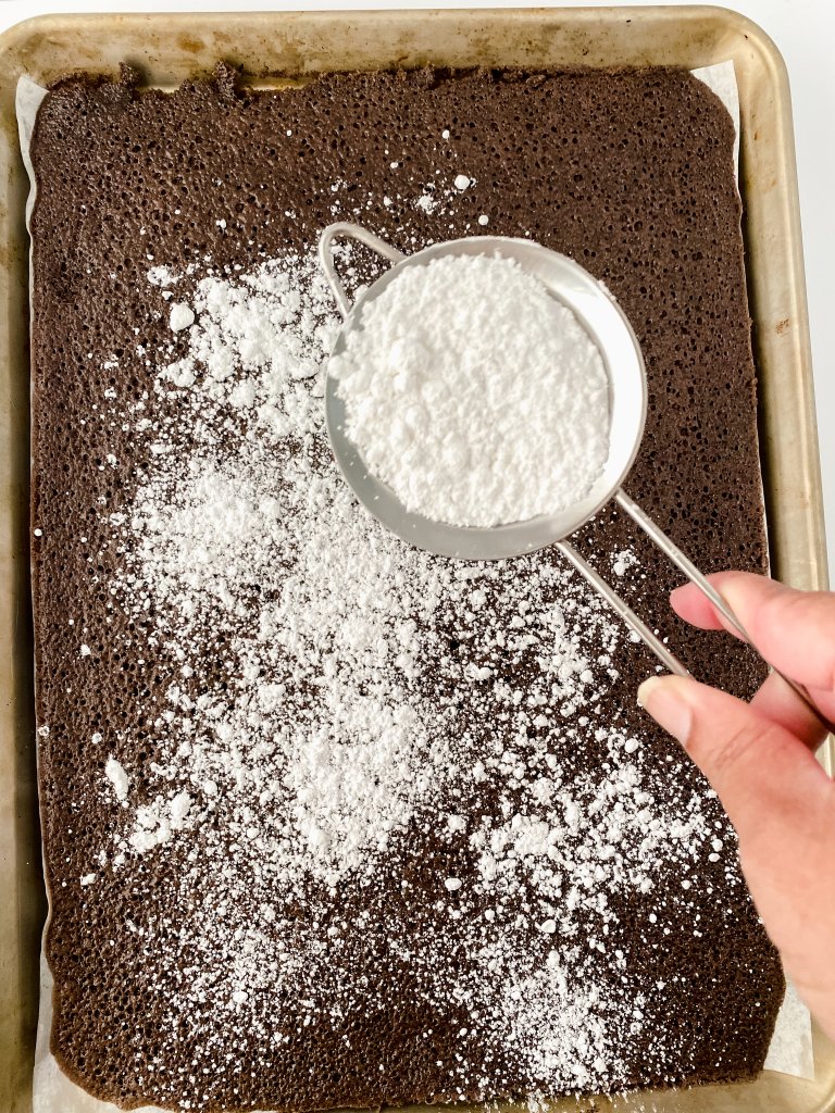 Overhead shot of powdered sugar being dusted on chocolate cake