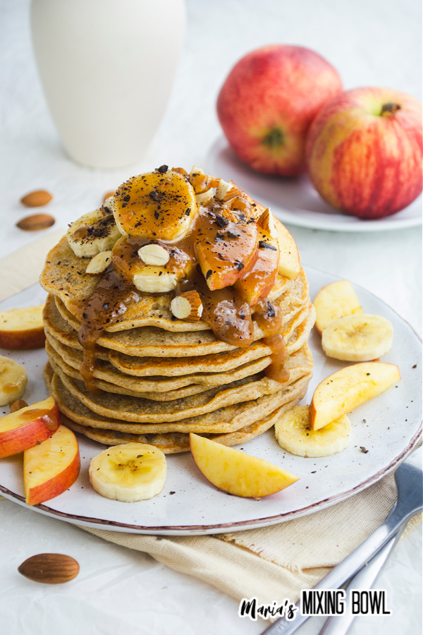 Stack of banoffee pancakes on plate with apples on plate in background