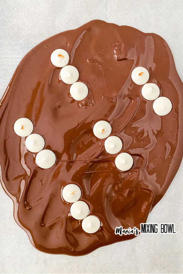 Melted chocolate with white chocolate melts as snowmen all over it