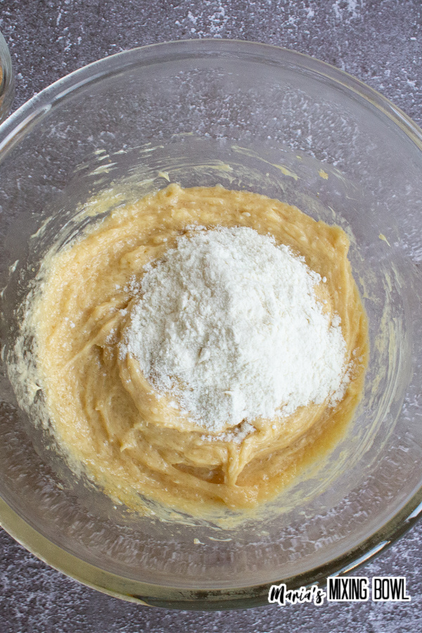 Bowl of wet cookie ingredients with flour ready to be mixed.