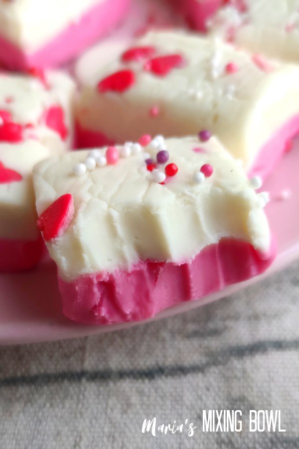pink and white layered fudge with a bite taken from it
