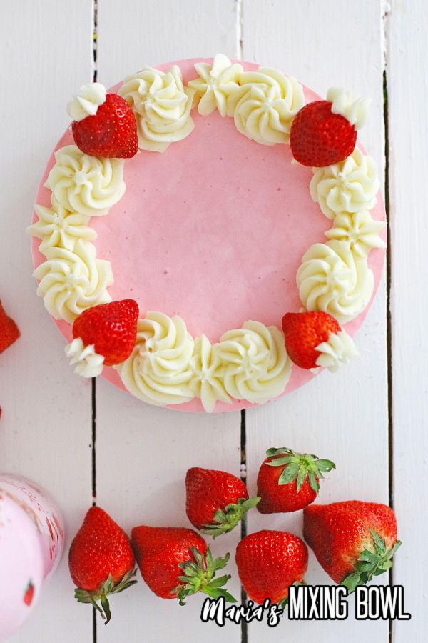 Overhead shot of strawberries and cream cheesecake decorated with whole strawberries and frosting