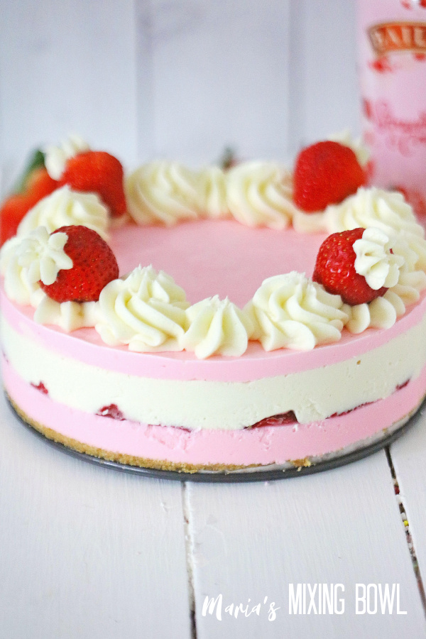 Whole strawberries and cream cheesecake decorated with strawberries and frosting