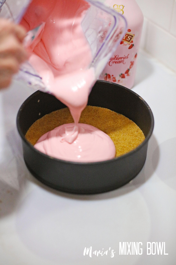 Pouring cheesecake batter over crust in springform pan