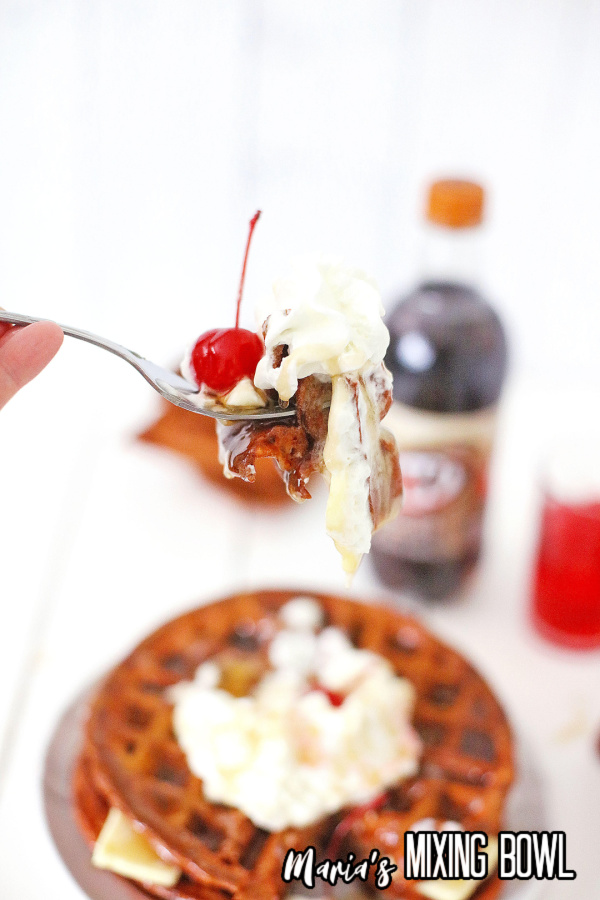 Closeup shot of forkful of root beer float waffle over plate of more waffles
