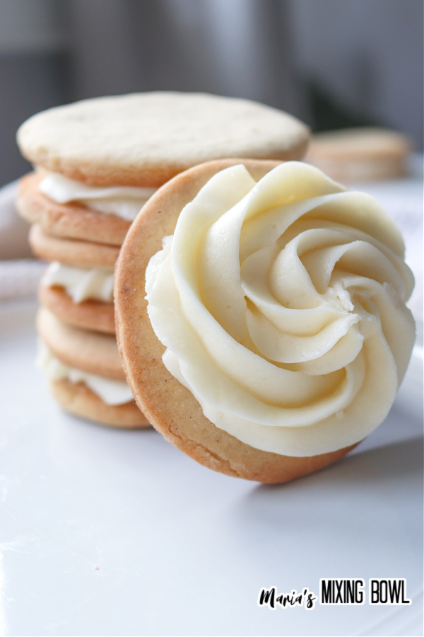 Closeup shot of frosted sugar cookie leaning against a stack of bourbon buttercream sugar cookies