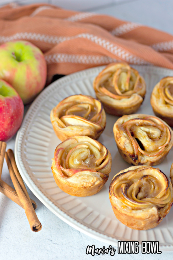 Apple rost tart puff pastries on plate next to apples and cinnamon sticks