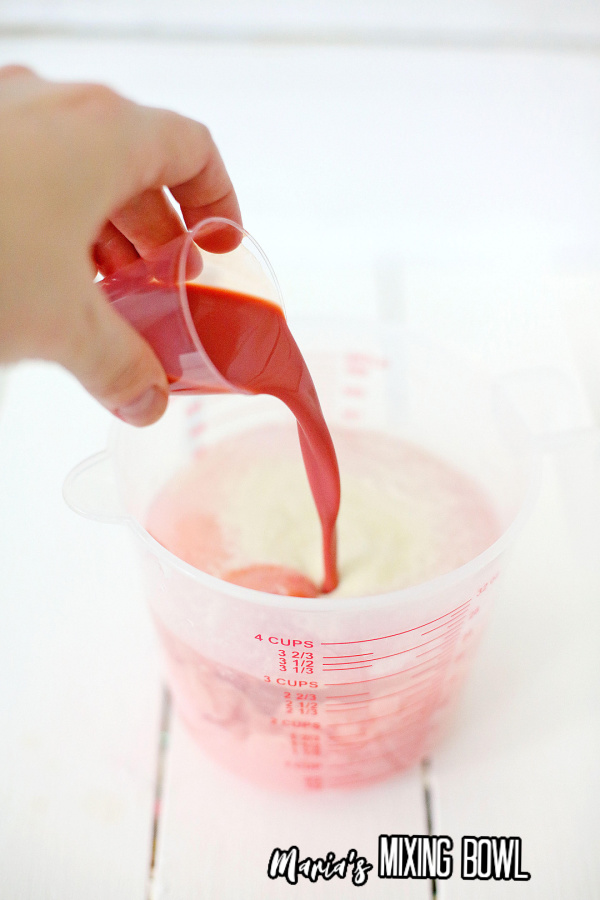 Hand pouring shot of Baileys Red Velvet Cupcake into Jello shot mixture