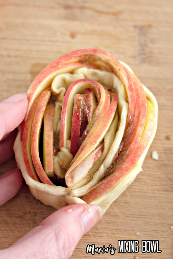 Overhead shot of hand holding rolled up tart ready to be baked