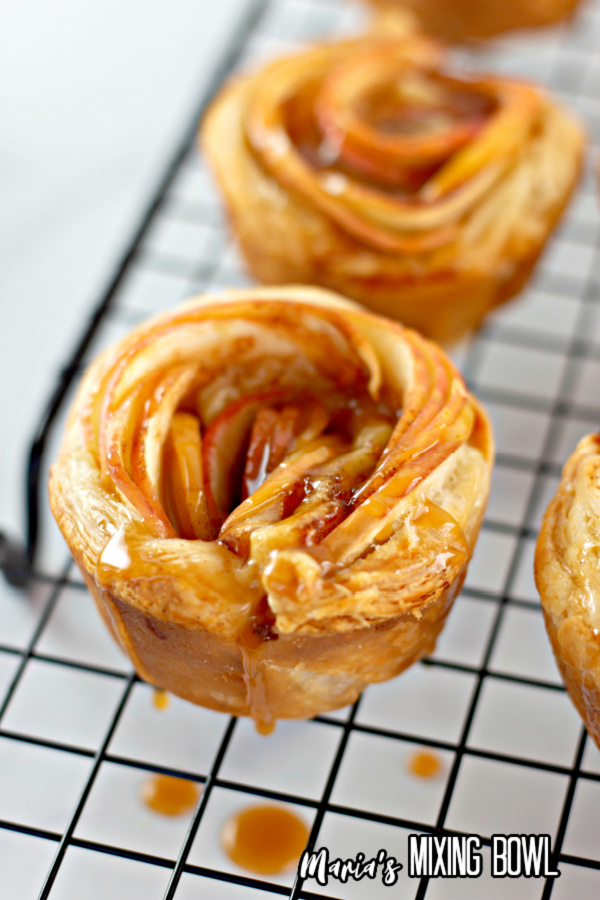 Closeup shot of apple rose tart puff pastry drizzled with caramel on cooling rack