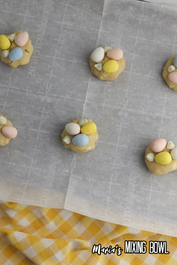 cookies on a baking sheet with parchment paper chocolate eggs on top of cookies 
