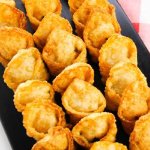 Creamy Crab Wontons lined up on a black cutting board