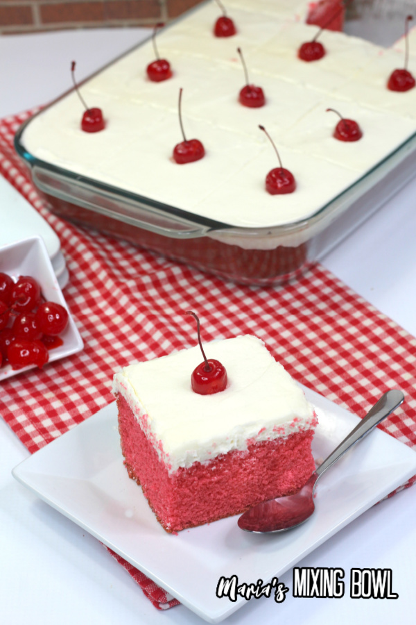 Cherry sheet cake on plate in front of baking dish with more sheet cake