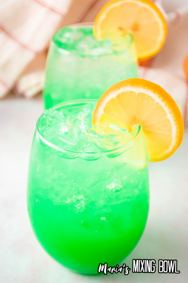 2 green drinks with orange slices and white and red napkin