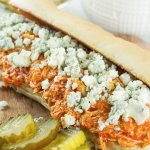 Slow Cooker Buffalo Chicken Cheesesteaks with pickles, blue cheese on dark board