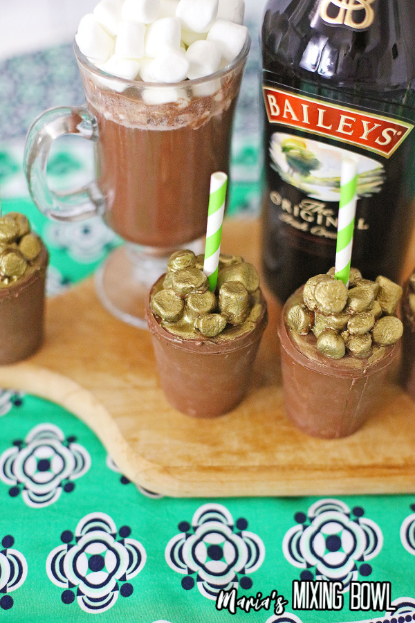Two spiked hot chocolate bombs in front of bottle of Baileys