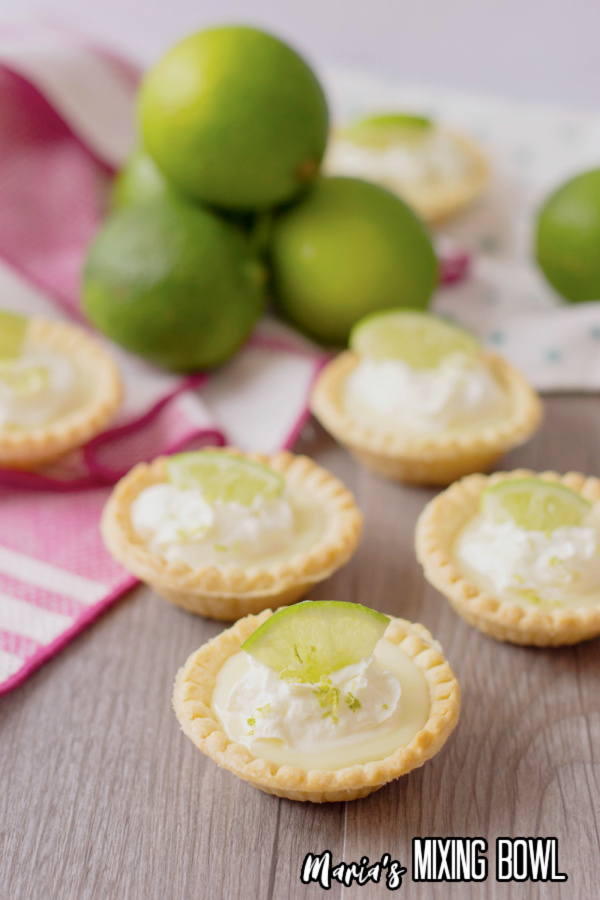 Mini lime pies on table with limes in background