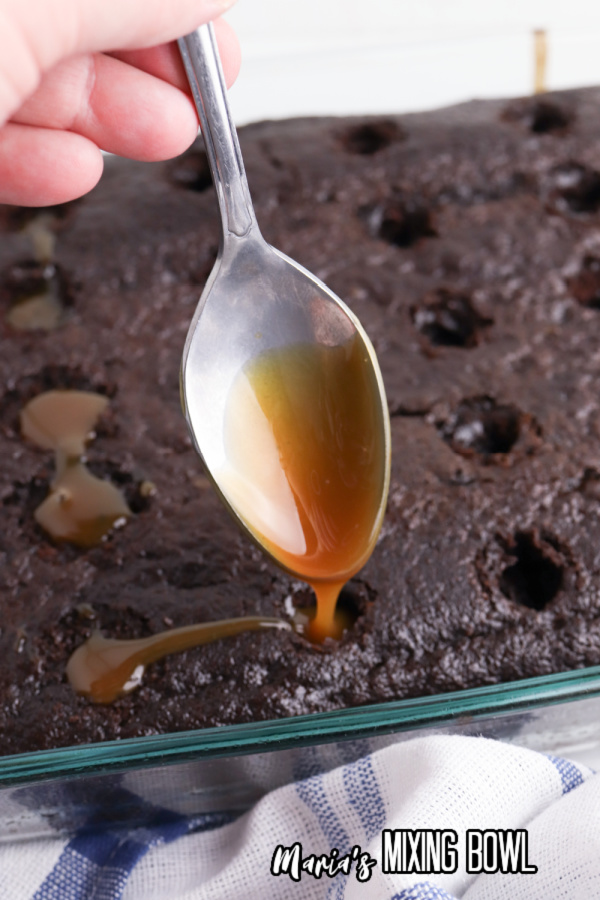 Spoon filling holes in cake with caramel