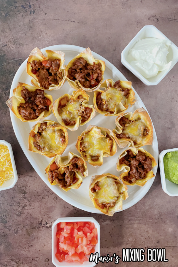 Easy Taco Cups Recipe on a white platter with sides for topping