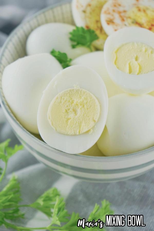 Closeup shot of bowlful of air fryer boiled eggs with one egg cut in half