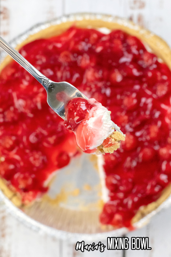 Overhead shot of forkful of cheesecake over cake pan with more no-bake cherry cheesecake