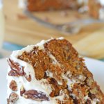 Carrot Cake Recipe on a white plate, carrot cake in background on wood board