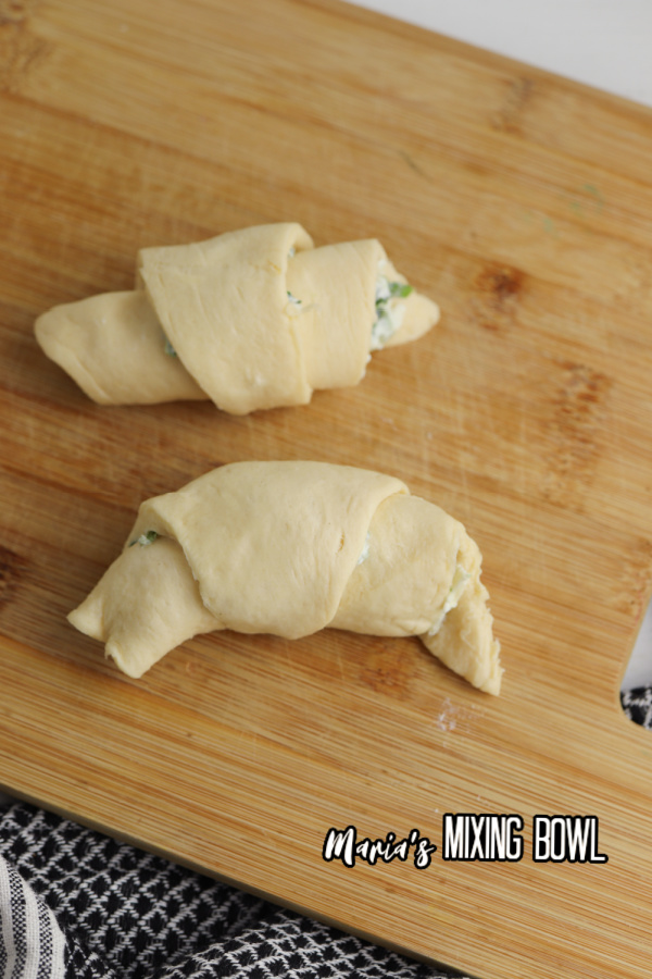 Uncooked spinach artichoke crescent rolls on cutting board