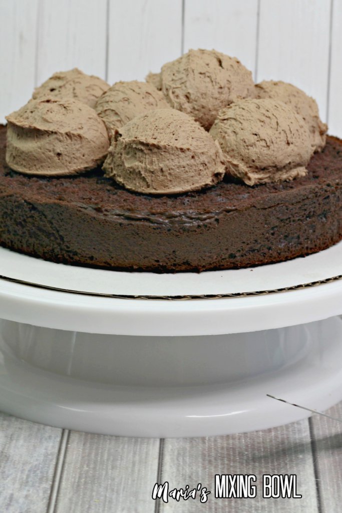 scoops of frosting on chocolate cake layer