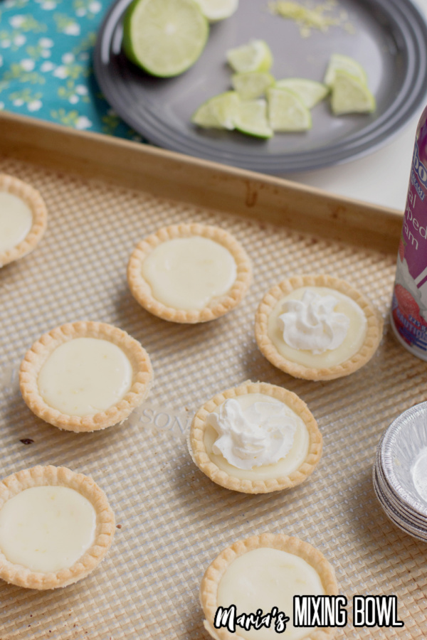 Mini lime pies being topped with whipped cream