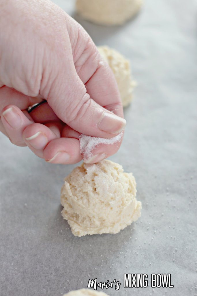 Hand sprinkling sugar over sugar cookie dough