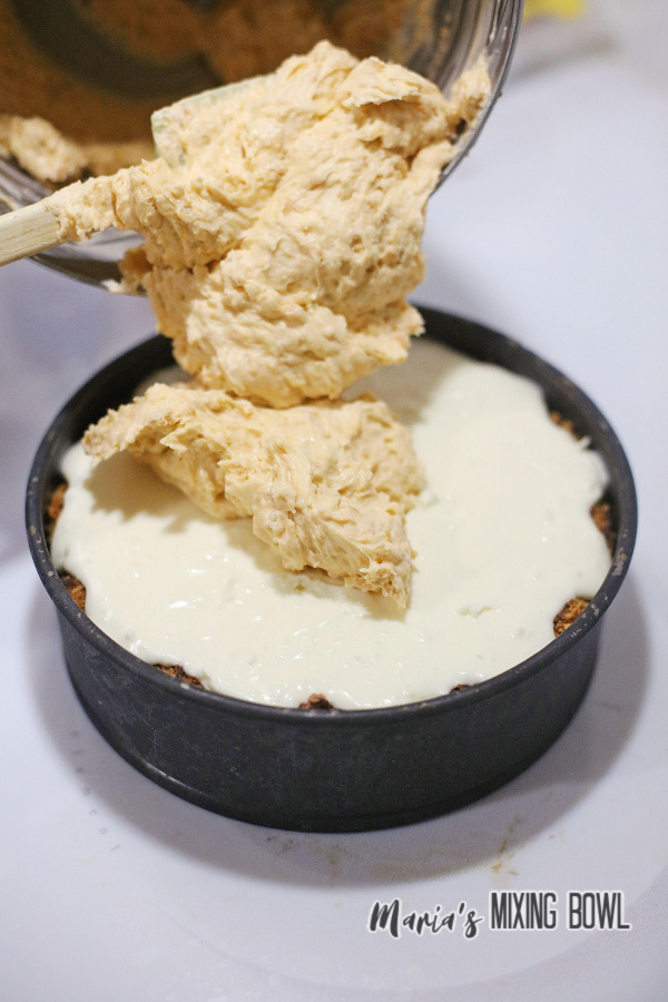 Top layer of coconut dream cookies cheesecake being added