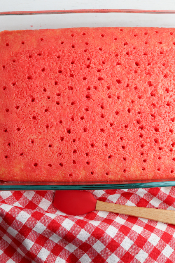 Overhead shot of cake with holes in it after jello being poured over it