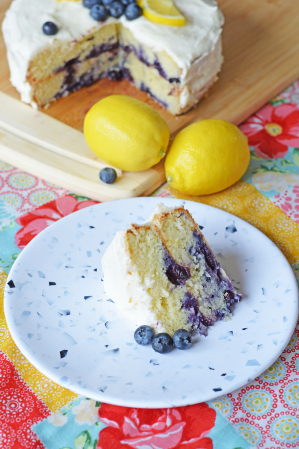 Lemon Blueberry Cake slice on blue plate with cake in background