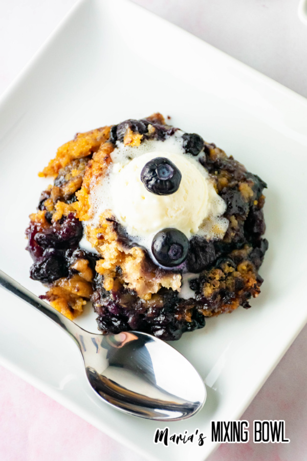 Slow Cooker Blueberry Cobbler on a white plate with a silver spoon