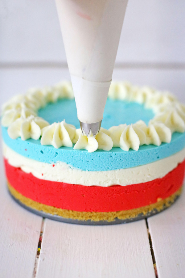 Patriotic Kool Aid cheesecake being decorated with frosting