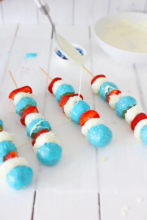 Donut hole kabobs being drizzled with white chocolate
