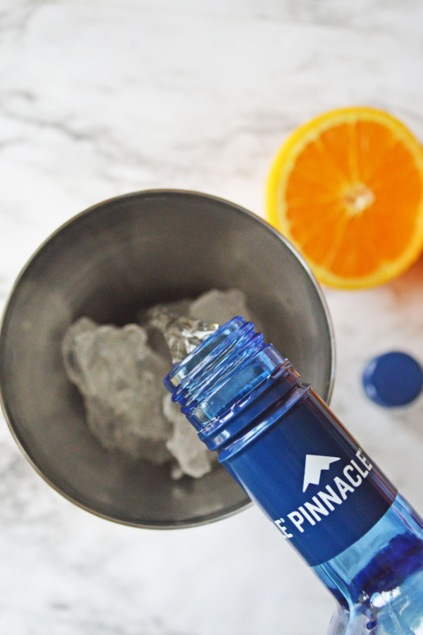 Overhead shot of vodka being poured into shaker with ice