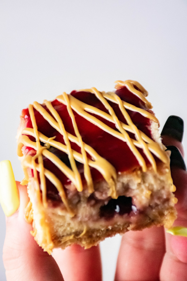 Closeup shot of hand holding peanut butter and jelly cheesecake bar