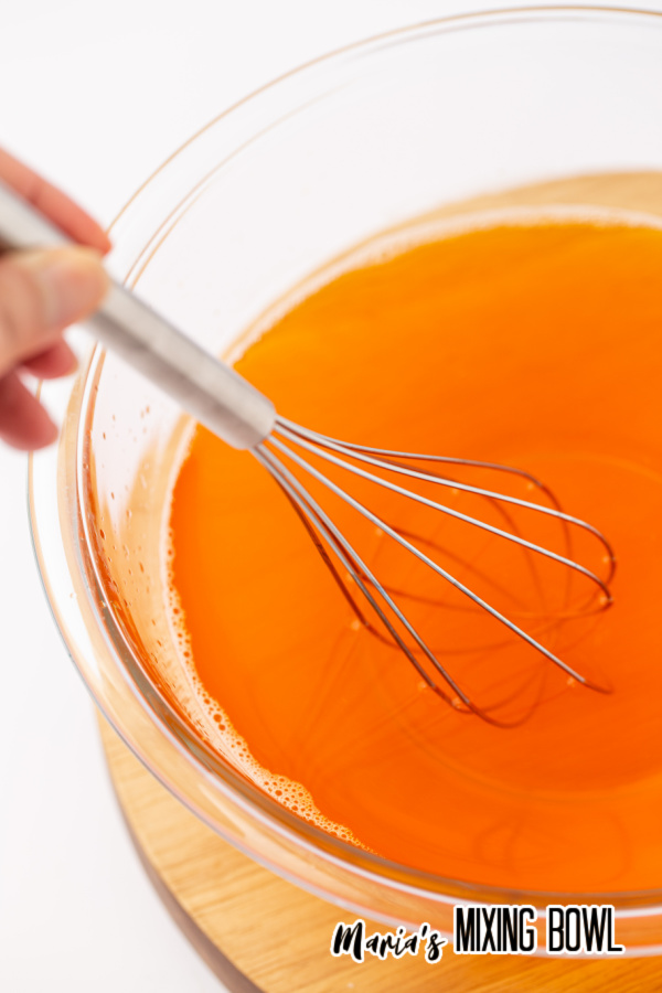 Whisk mixing orange Jello in bowl