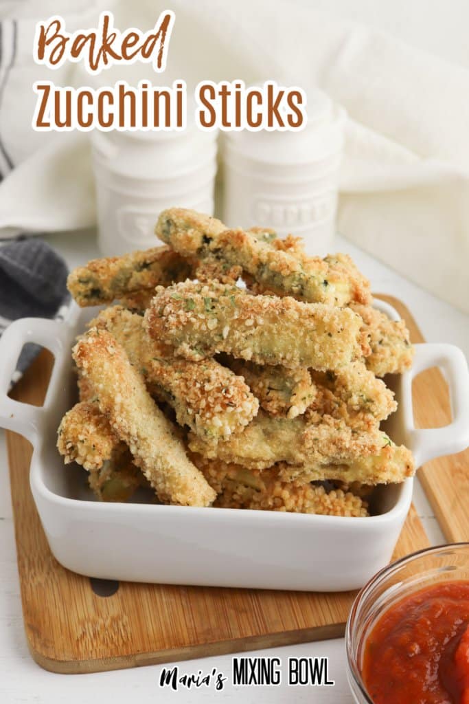 baked zucchini sticks in a white bowl on a wooden cutting board