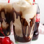 Two glasses of black cow floats with paper straws with text for pinterest