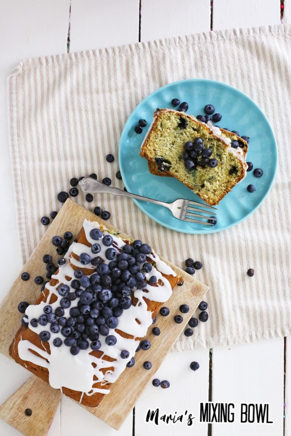 birds eye image of a loaf blueberry banana bread, and a slice on a blue plate
