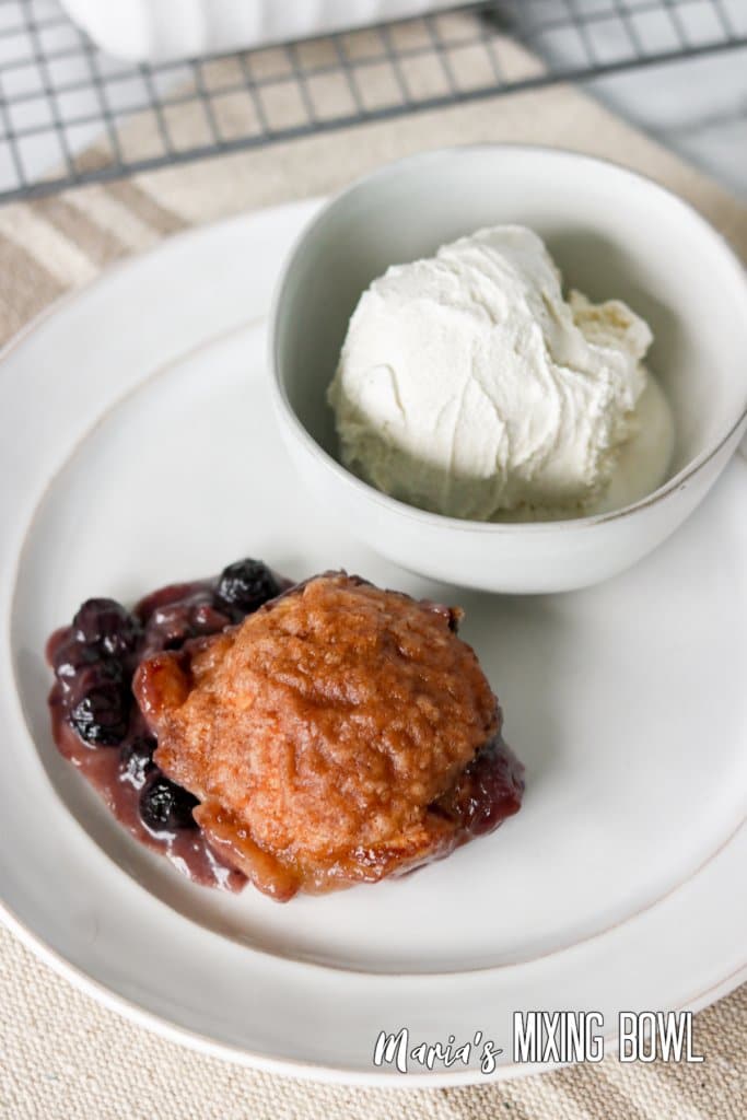 blueberry dumplings on a plate with a bowl of ice cream