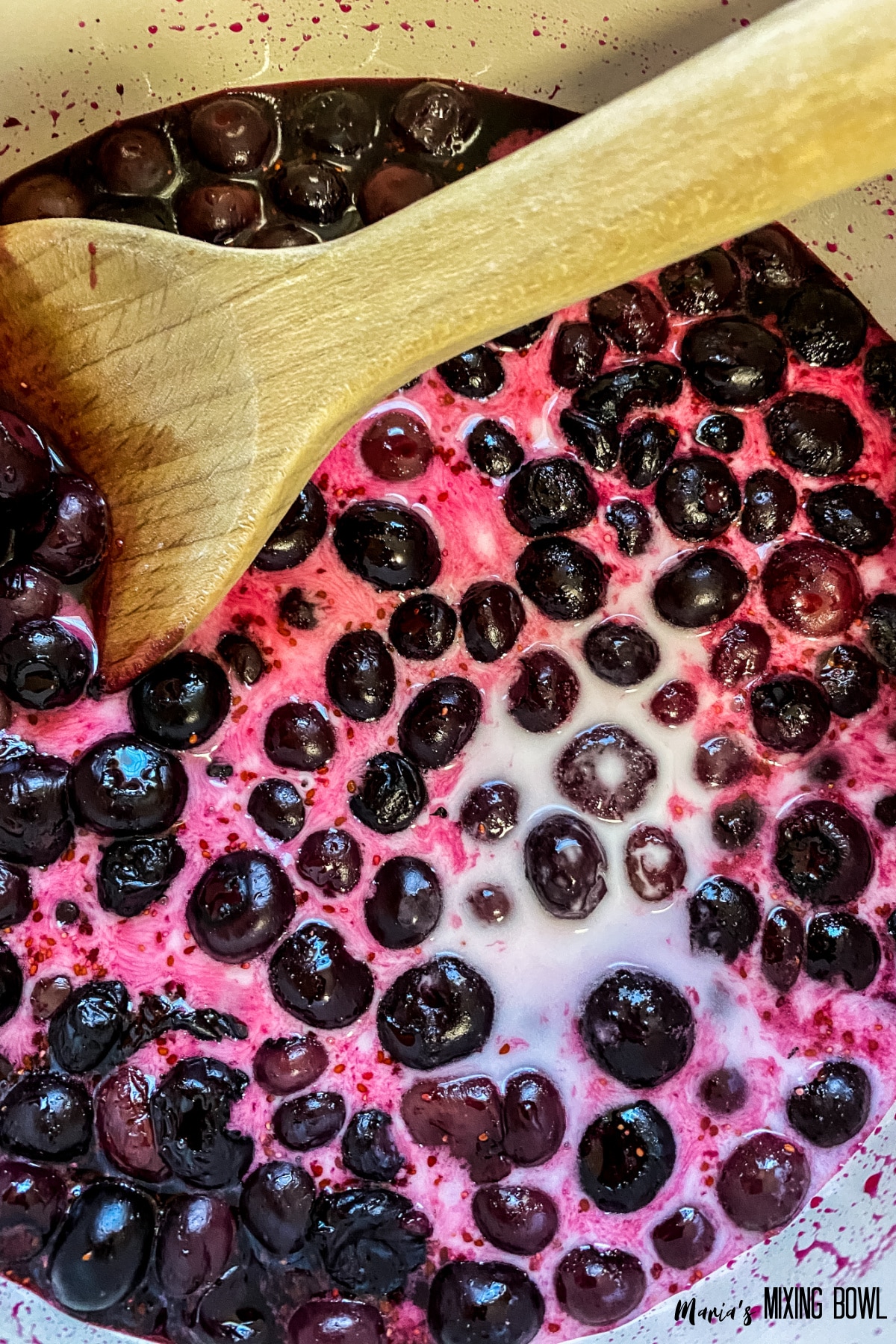 berries and sugar in a saucepan with a wooden spoon