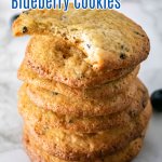 stack of crispy blueberry cookies on a marble counter with top one with a bite missing