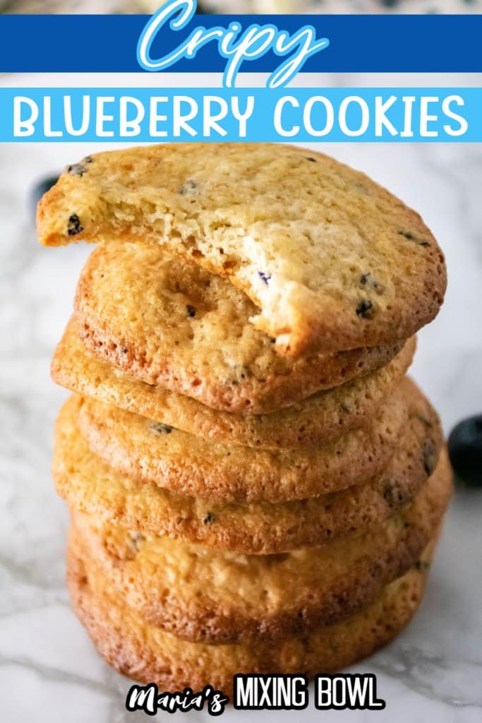 stack of crispy blueberry cookies on a marble counter with top one with a bite missing with text for pinterest